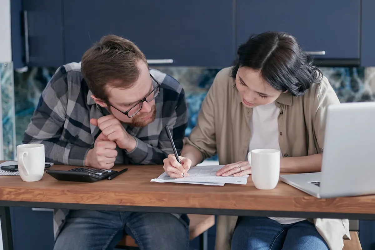 Pareja revisando papeles y cuentas juntos en la mesa de casa.